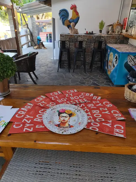 The bar and its rooster painting, a red pop-art placemat on the table