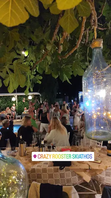 An evening crowd beneath the fig tree, a glowing bottle lamp in front