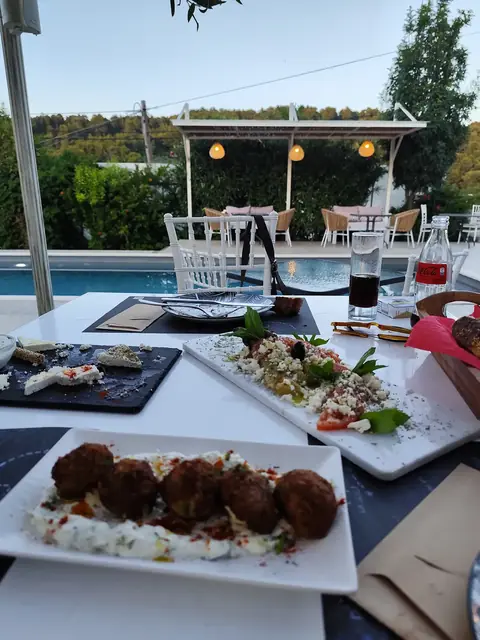 Fried meatballs and salads on a table beside the pool