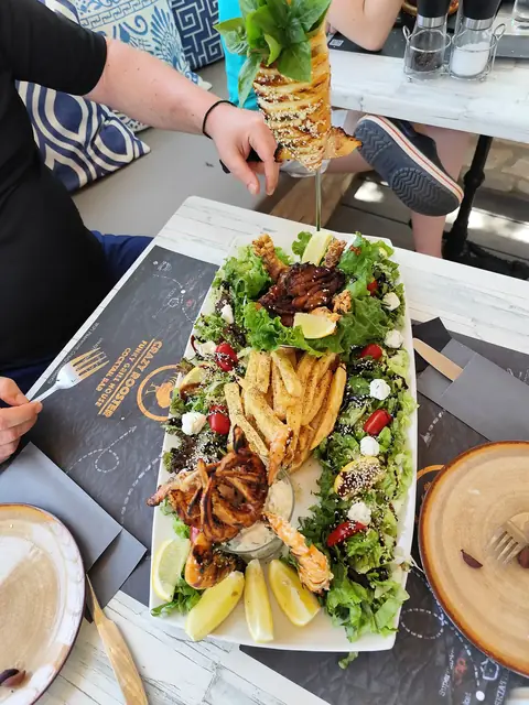 A mixed platter with fries and salad, a pineapple cocktail beside it