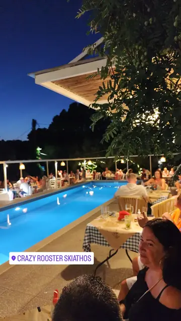 Guests at the tables along the lit pool at dusk