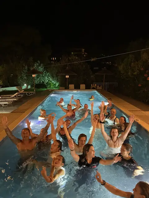 Guests in the pool with their arms in the air on a party night