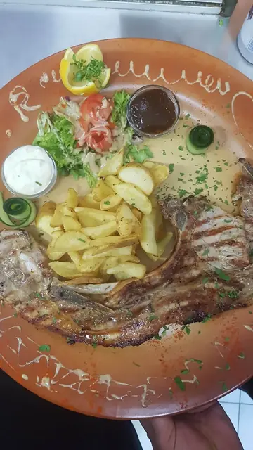 Grilled meat with fries and dips on a clay plate