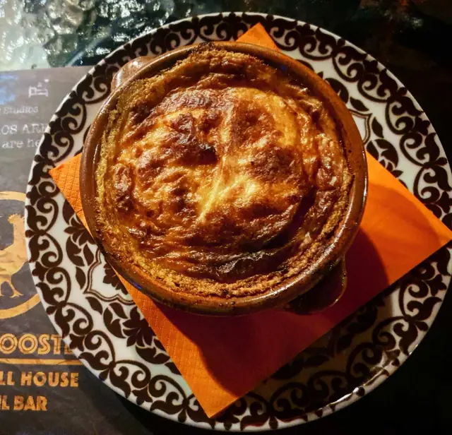 A golden oven-baked dish in a patterned clay bowl