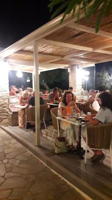 Guests at dinner under the lit pergola