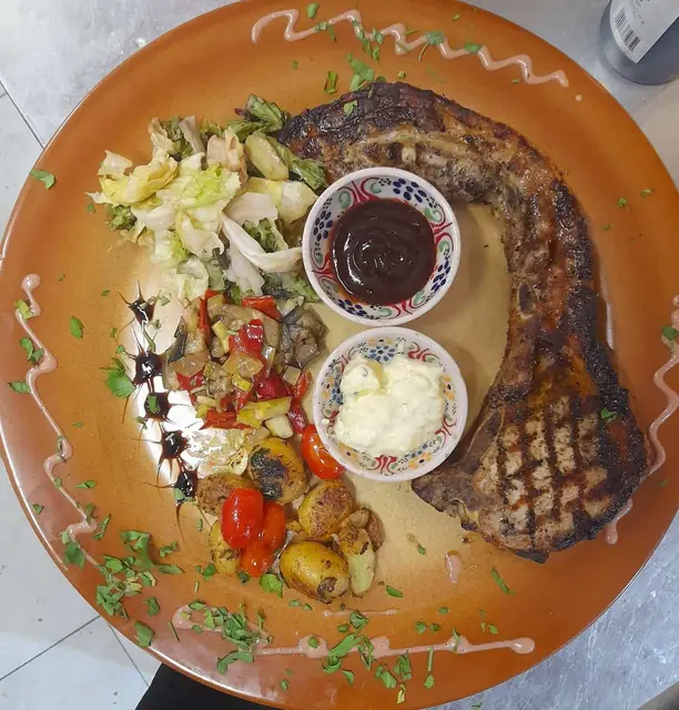 Grilled steak with vegetables and two dips on a terracotta plate