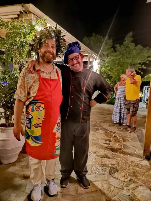 Two of the Crazy Rooster crew in aprons, one wearing a crown of leaves