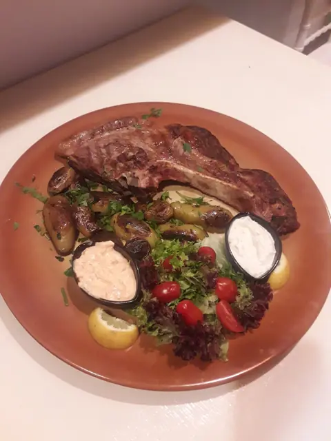 A grilled steak with salad and a dip