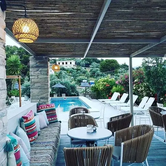 Striped sofas beside the pool, the green hills of Skiathos beyond
