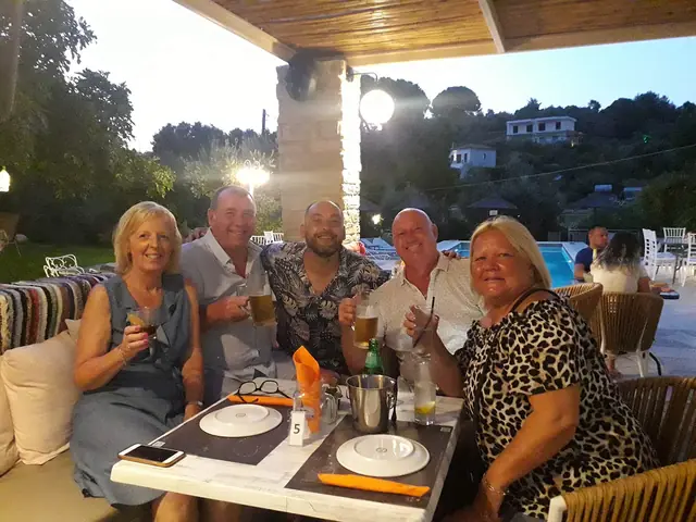 Friends raising their glasses at a table by the pool